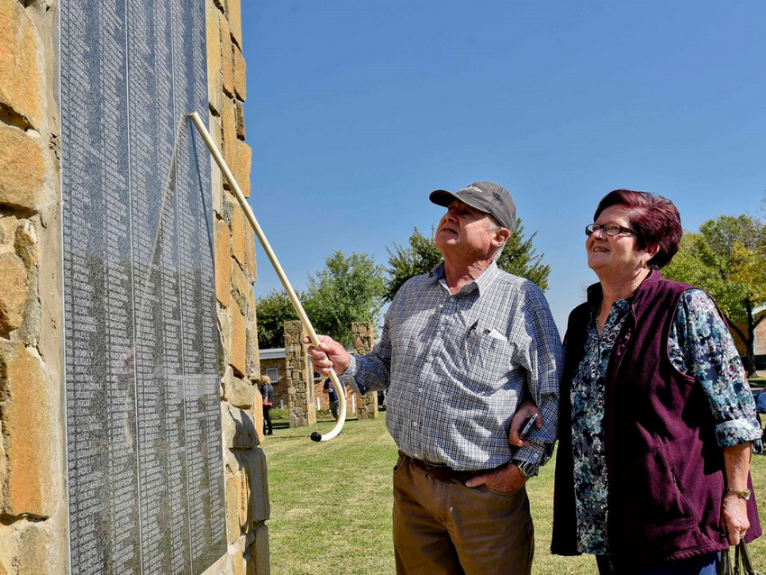 Visitors reading names on a memorial panel